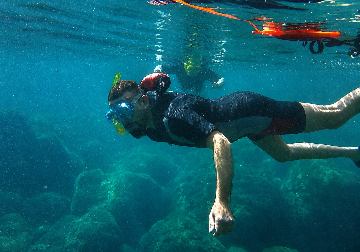 Persona che pratica snorkeling in acque cristalline, con maschera e boccaglio.
