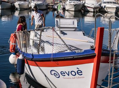 Barca turistica Evoè nel porto, con scafo bianco e rosso.